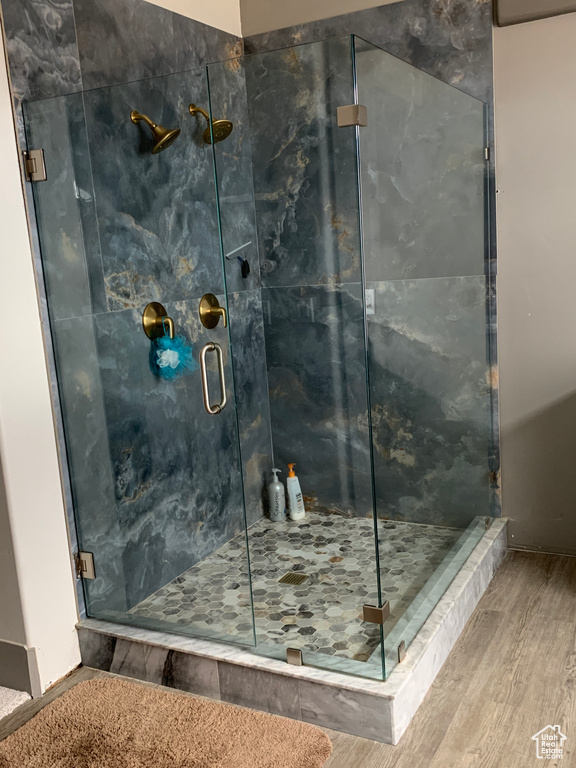 Full bathroom featuring a marble finish shower and wood finished floors