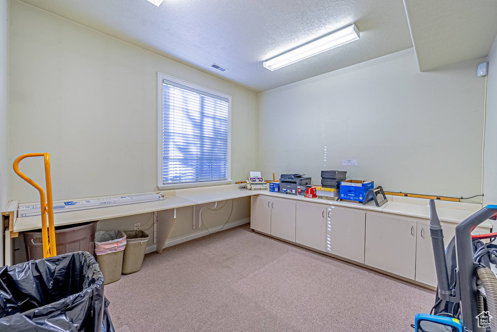 Office space featuring visible vents, light carpet, and a textured ceiling