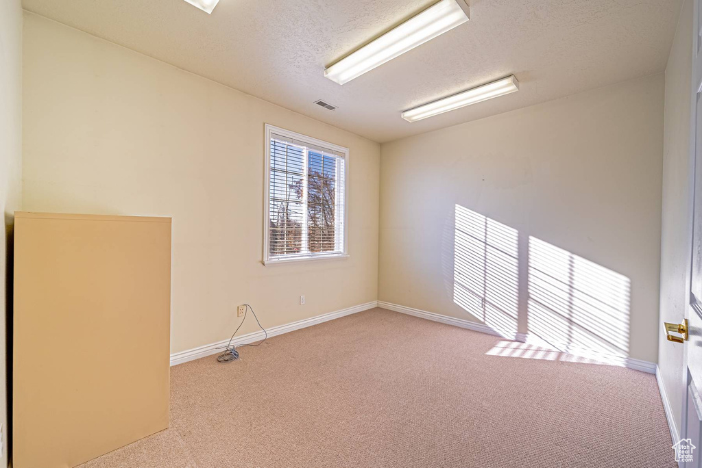Spare room with a textured ceiling, carpet, visible vents, and baseboards