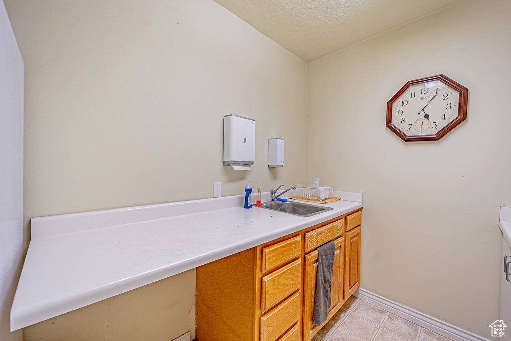 Bathroom with vanity, baseboards, a textured ceiling, and tile patterned floors