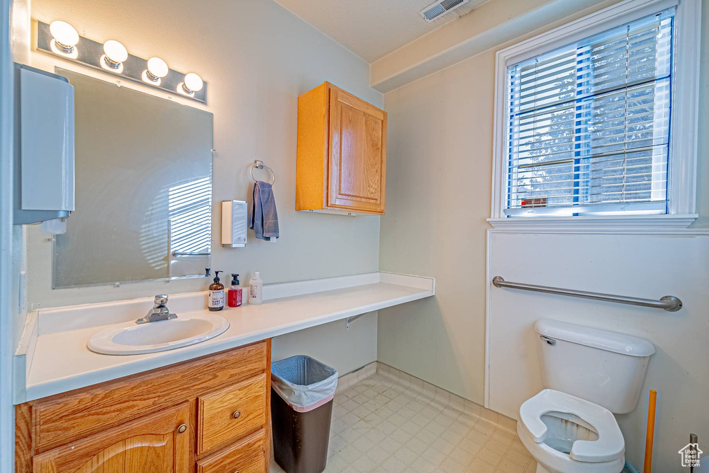 Bathroom featuring a healthy amount of sunlight, tile patterned floors, toilet, and vanity
