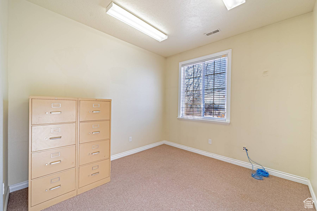 Spare room with light carpet, baseboards, visible vents, and a textured ceiling