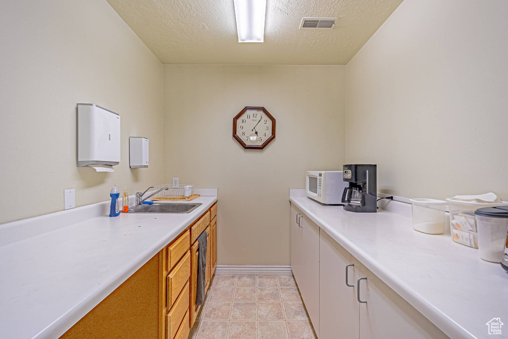 Interior space featuring light countertops, visible vents, white microwave, a sink, and a textured ceiling
