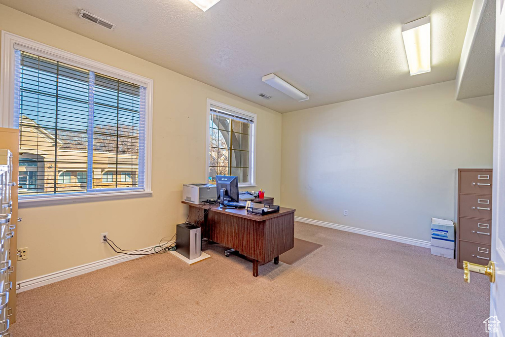 Home office featuring a textured ceiling, carpet floors, visible vents, and baseboards