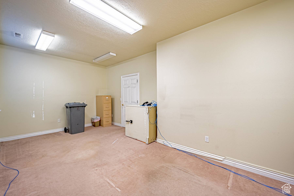 Empty room featuring light carpet, baseboards, visible vents, and a textured ceiling