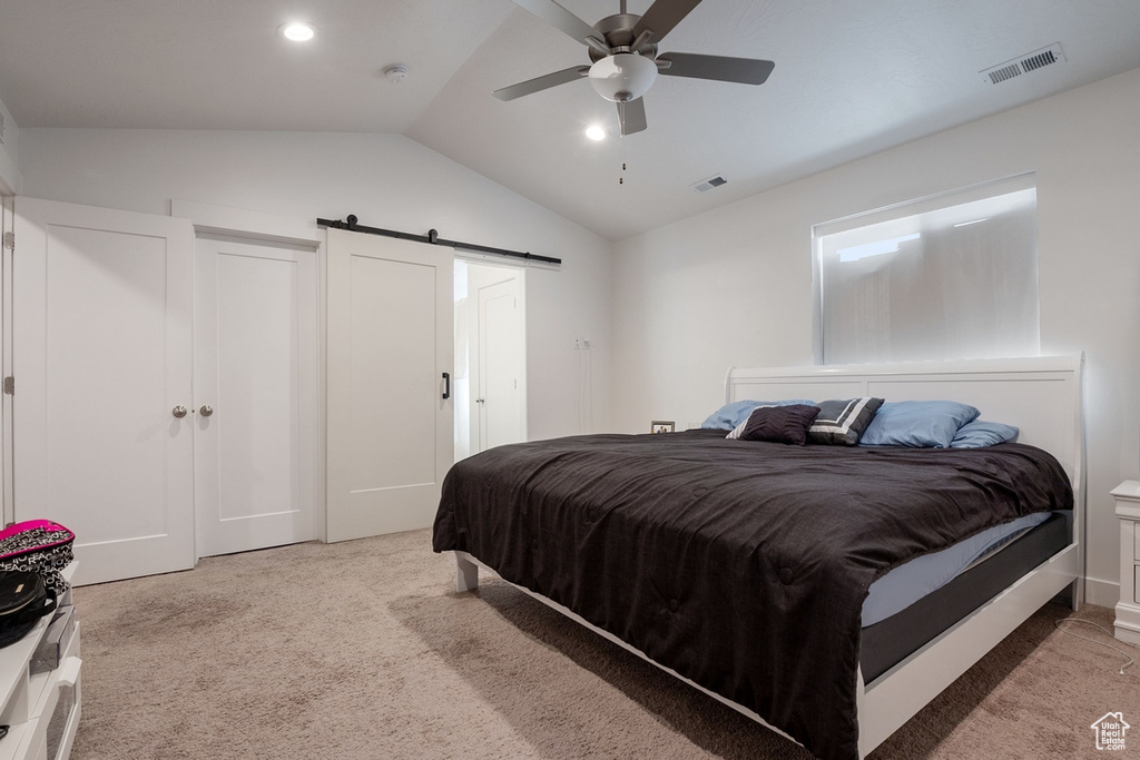 Carpeted bedroom featuring lofted ceiling, a barn door, visible vents, and a ceiling fan