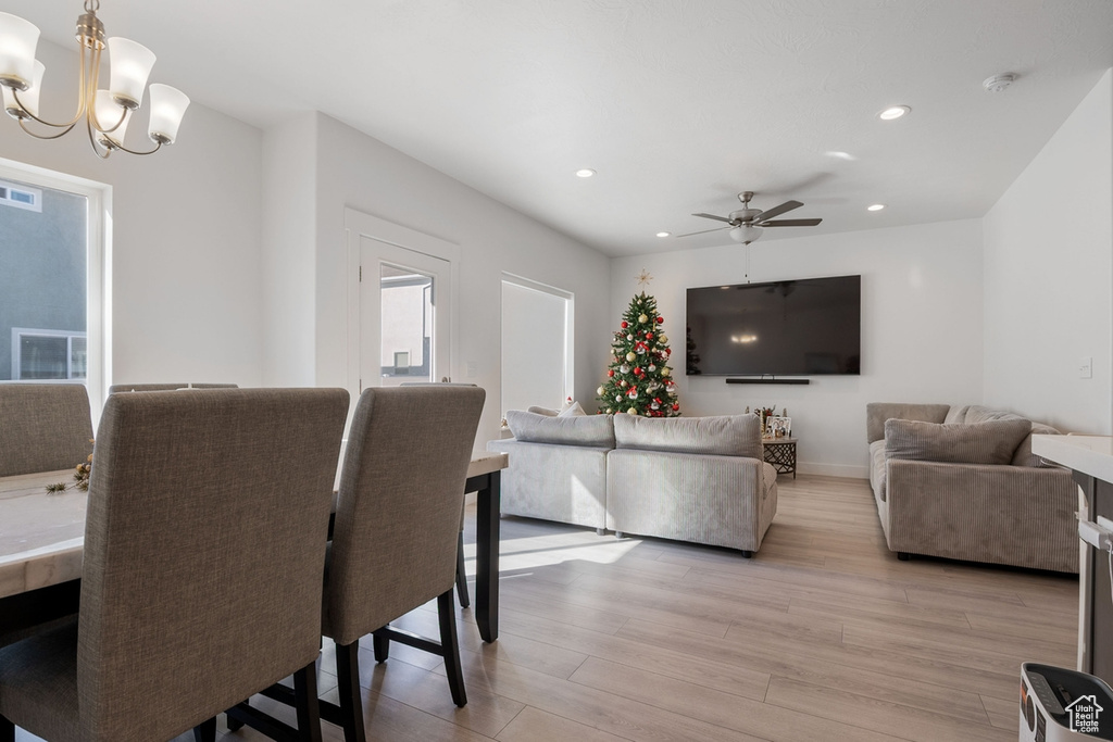 Dining room with light wood-style flooring, recessed lighting, ceiling fan with notable chandelier, visible vents, and baseboards