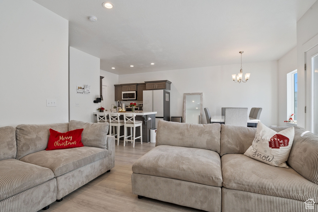 Living room with light wood-type flooring, a notable chandelier, and recessed lighting