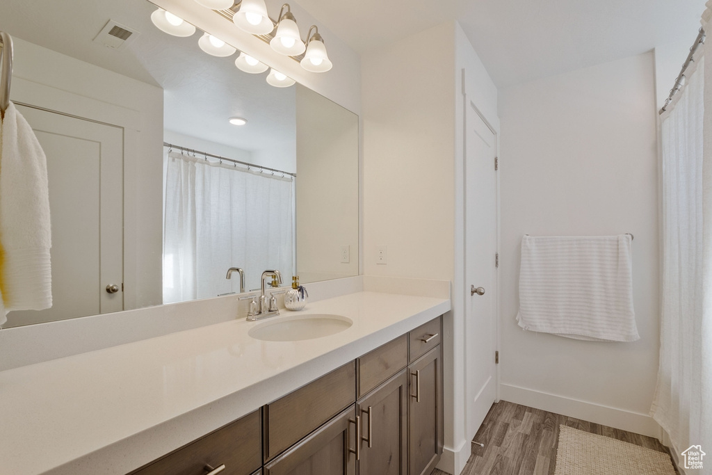 Full bath featuring baseboards, visible vents, wood finished floors, and vanity