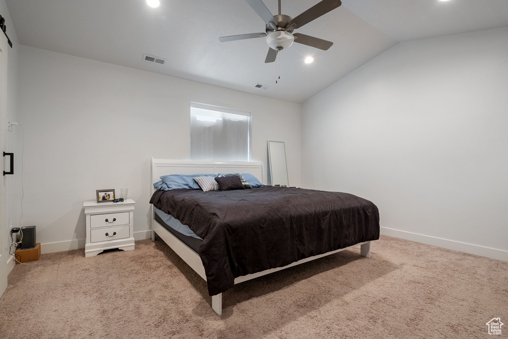 Carpeted bedroom with baseboards, visible vents, vaulted ceiling, and a ceiling fan