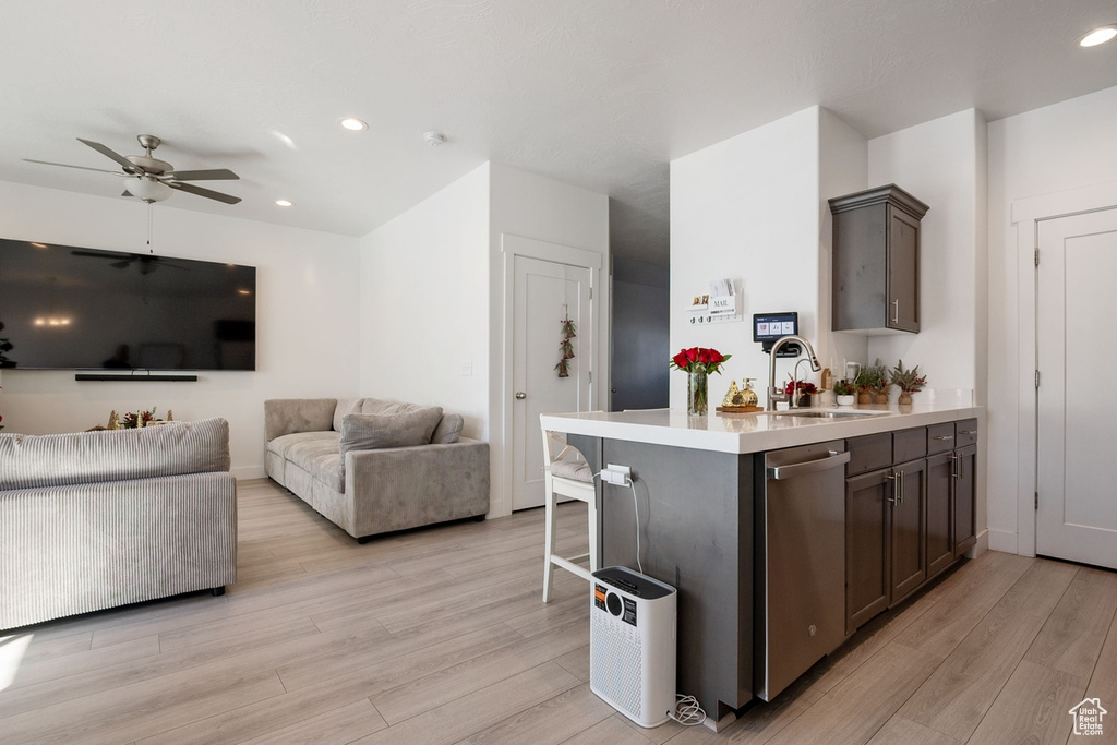 Kitchen featuring light countertops, a sink, light wood-style flooring, and stainless steel dishwasher