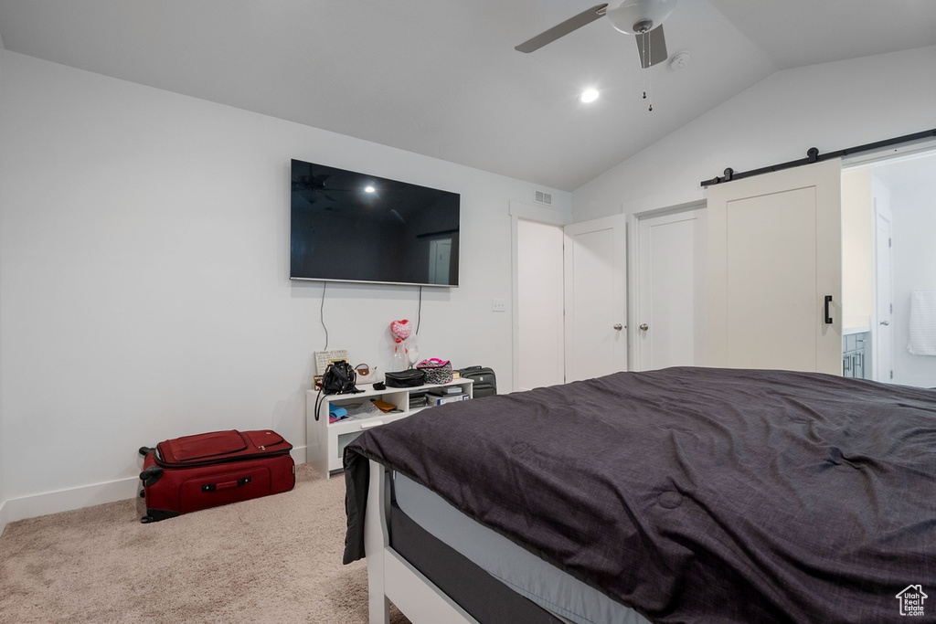 Carpeted bedroom with vaulted ceiling, a barn door, a ceiling fan, and baseboards