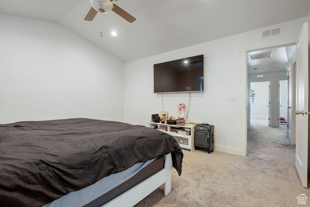 Bedroom featuring light colored carpet, visible vents, vaulted ceiling, and ceiling fan