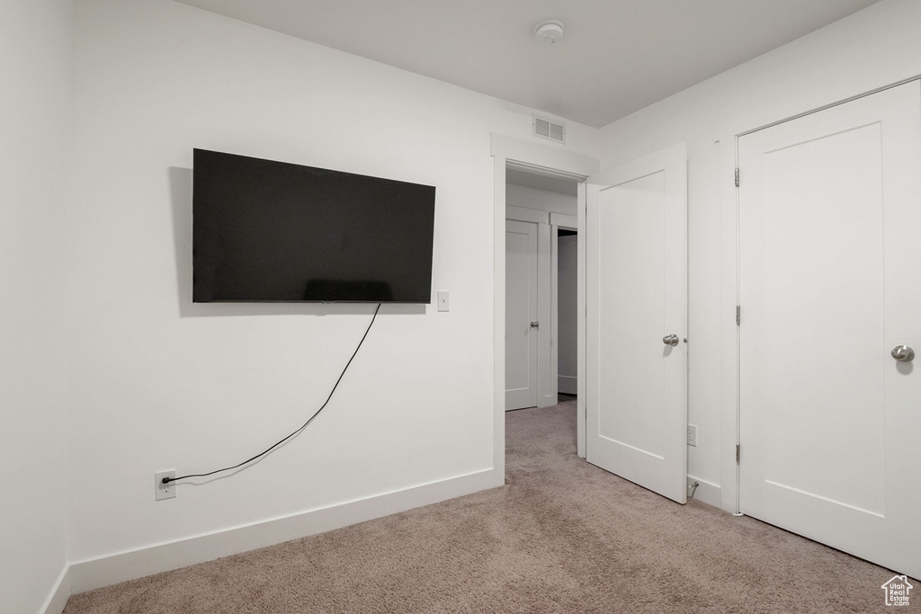 Unfurnished bedroom with a closet, carpet, visible vents, and baseboards