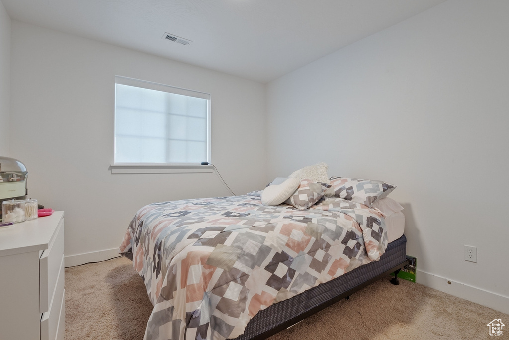 Bedroom with baseboards, visible vents, and light colored carpet