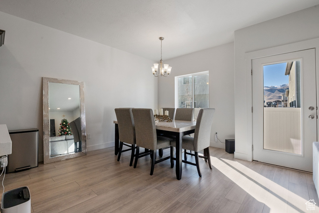 Dining area featuring an inviting chandelier, light wood-style flooring, and baseboards