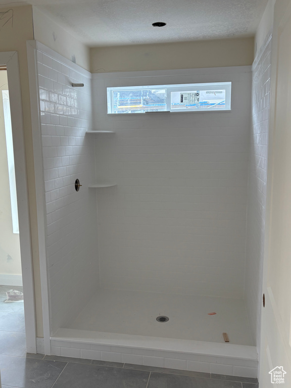 Bathroom with a wealth of natural light, tile patterned floors, and a stall shower