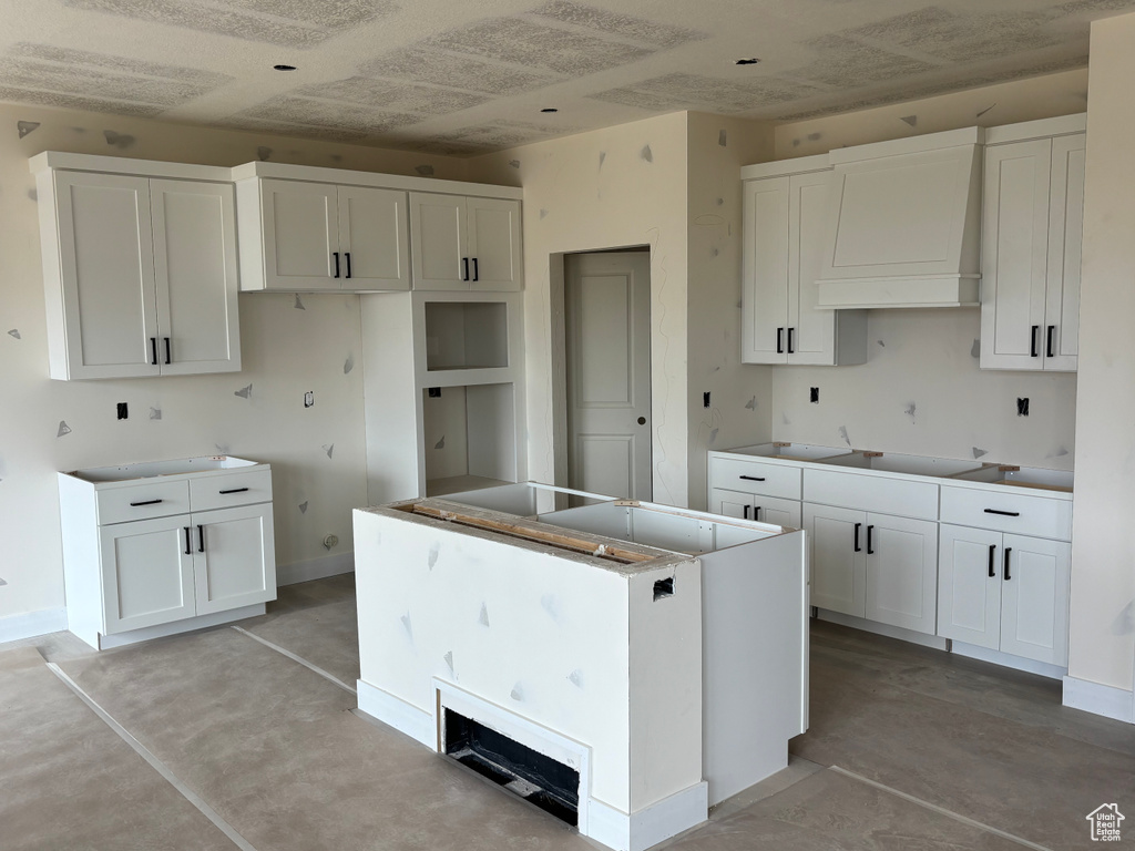 Kitchen featuring premium range hood, concrete flooring, white cabinets, and a kitchen island