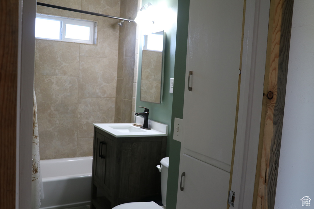 Bathroom with toilet, vanity, and shower / bathtub combination with curtain