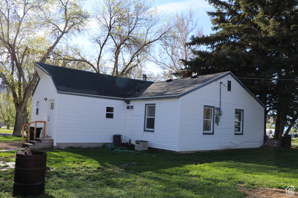 View of property exterior with a lawn and roof with shingles