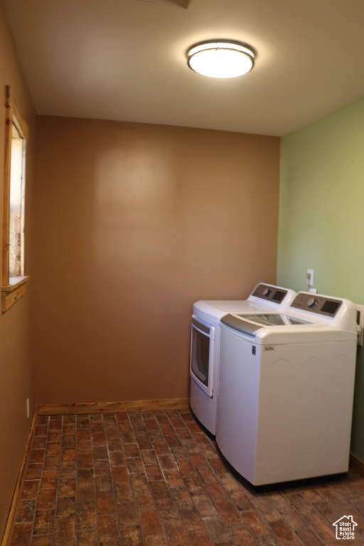 Laundry room featuring washer and dryer and brick floors
