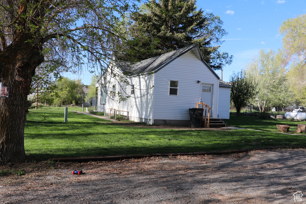 View of property exterior with a yard and entry steps