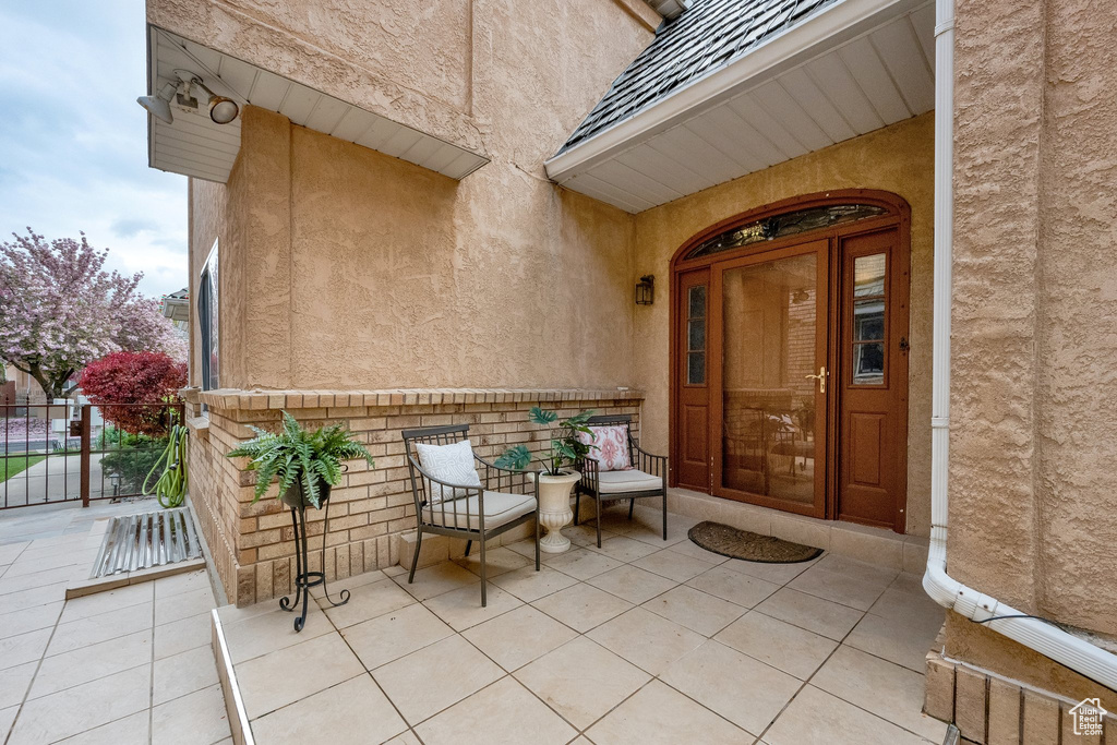 Entrance to property featuring fence, stucco siding, and a patio area
