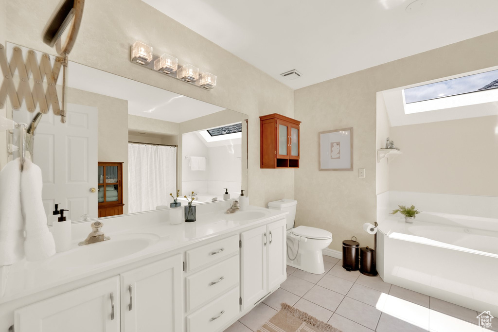 Full bath with visible vents, double vanity, toilet, a sink, and a skylight