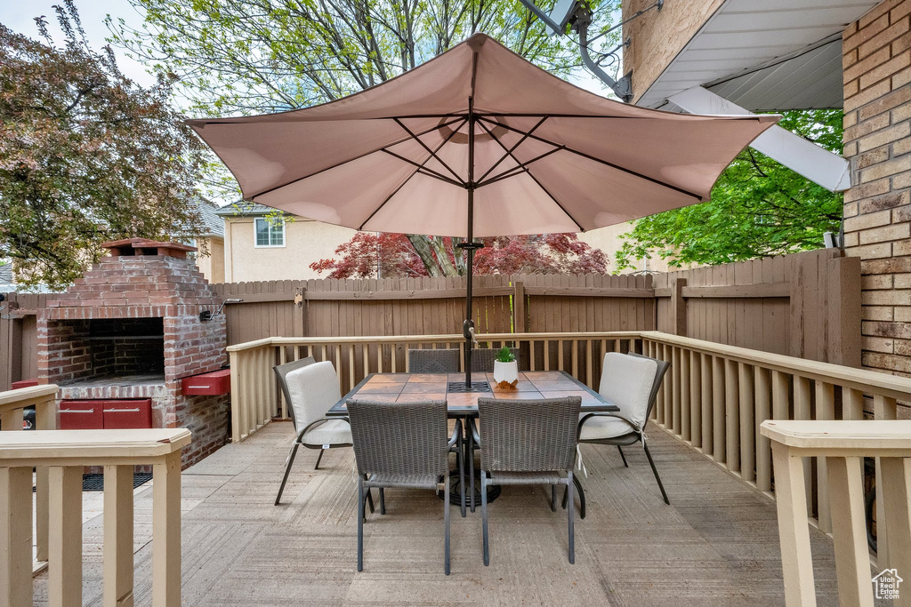 View of patio / terrace with fence, outdoor dining area, and a brick fireplace