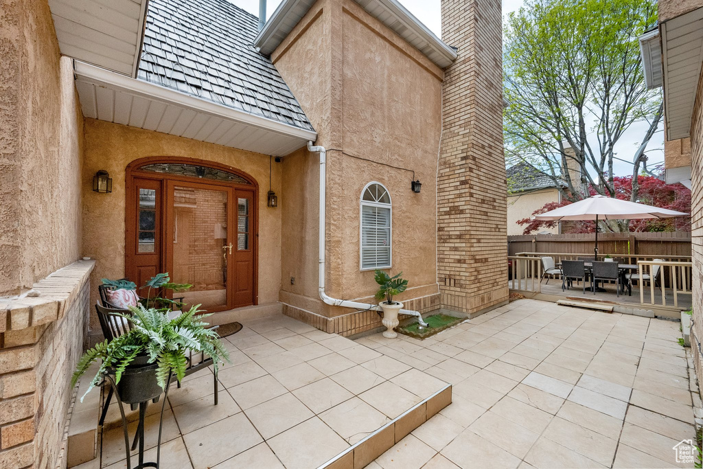 Doorway to property featuring fence, a patio, outdoor dining area, and stucco siding