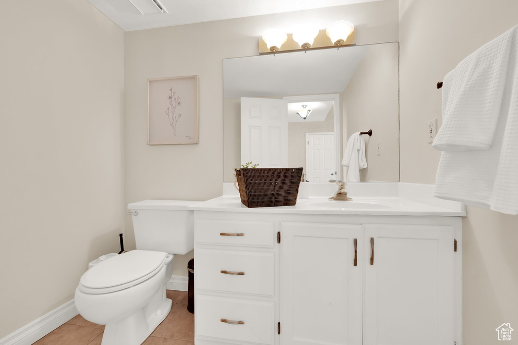 Half bathroom with tile patterned flooring, baseboards, toilet, and vanity