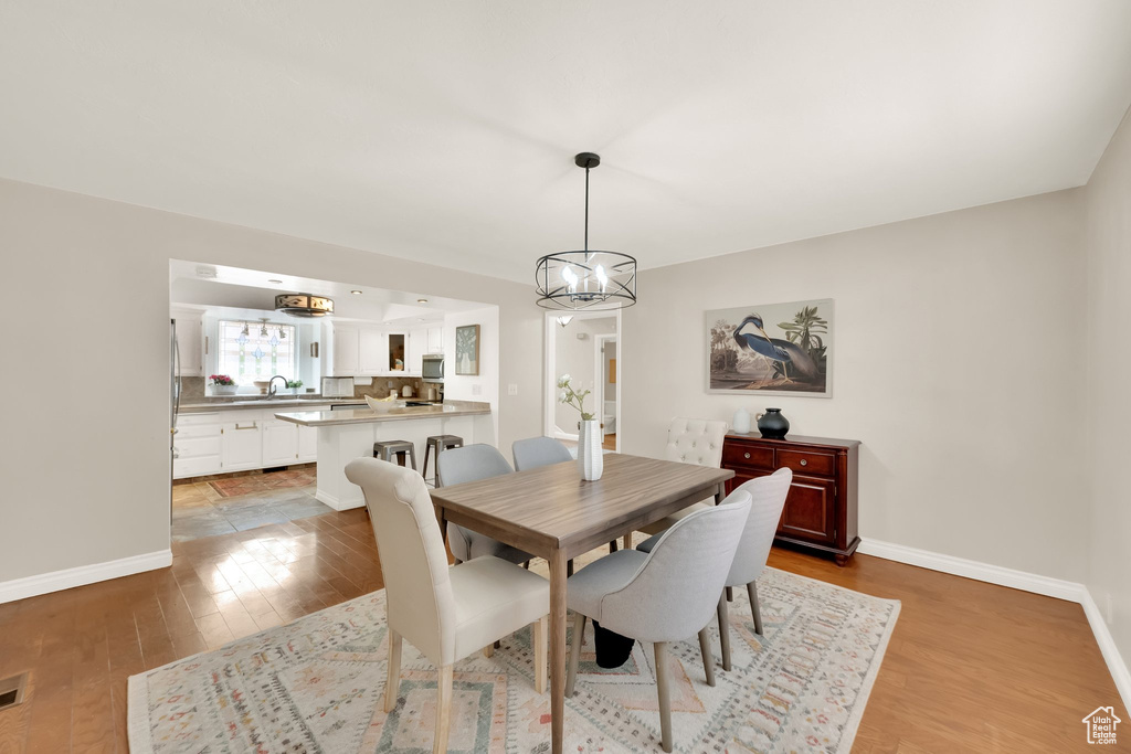 Dining room featuring light wood-style floors, baseboards, and a notable chandelier