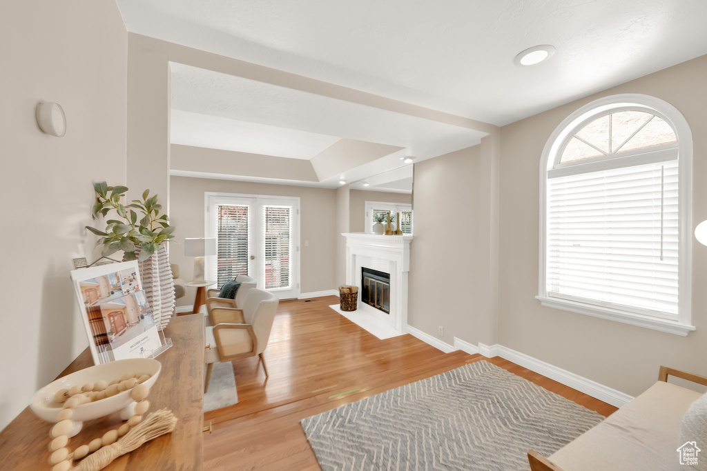 Living room featuring light wood-type flooring, a fireplace with flush hearth, and baseboards