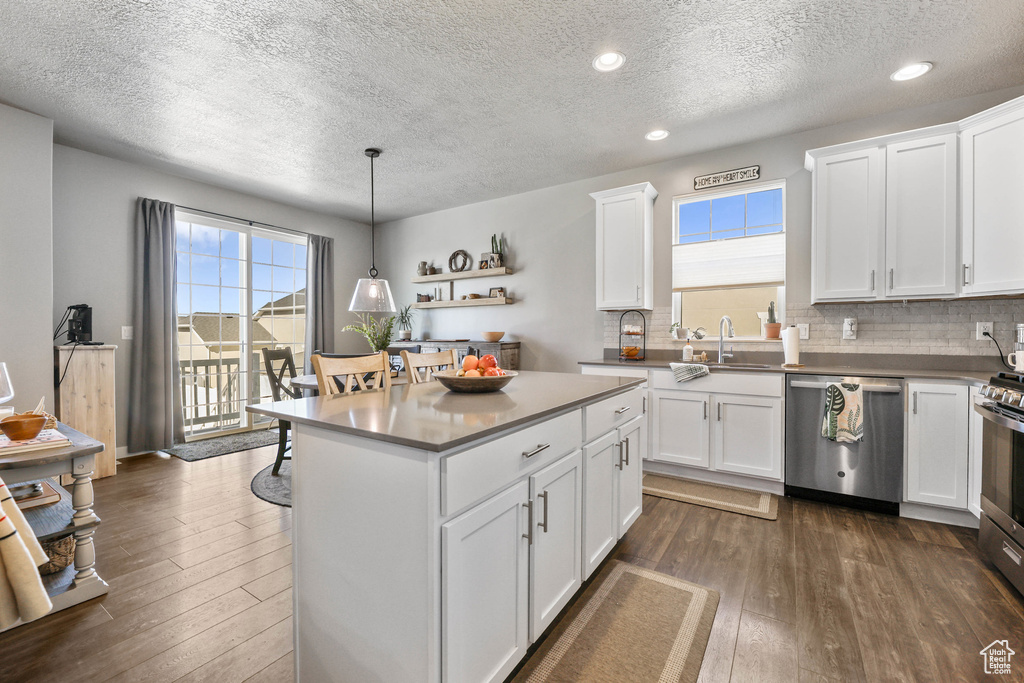 Kitchen with decorative backsplash, dark wood-type flooring, stainless steel appliances, white cabinetry, and a sink
