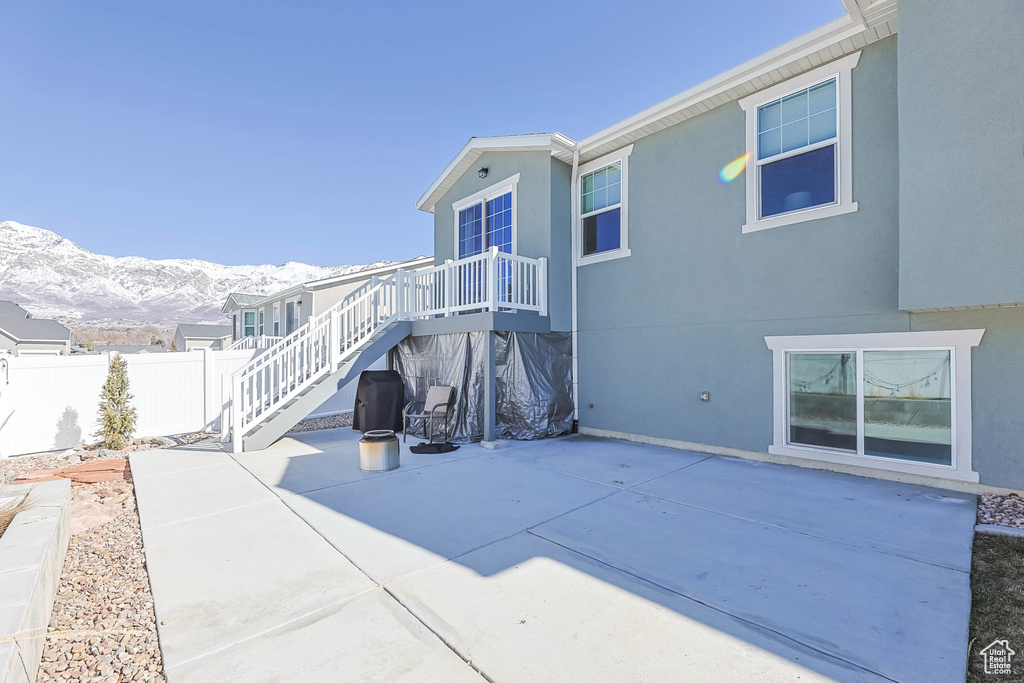 Back of house featuring a patio, stucco siding, fence, a mountain view, and stairs