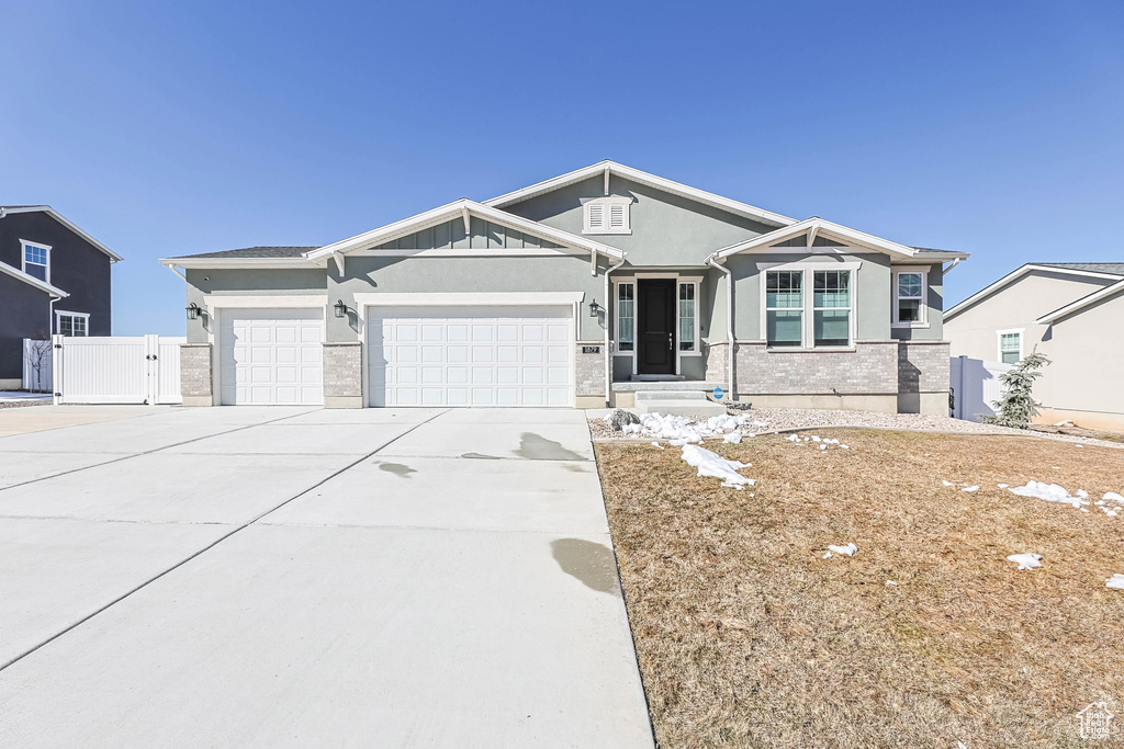 Craftsman inspired home with a garage, concrete driveway, a gate, fence, and stucco siding