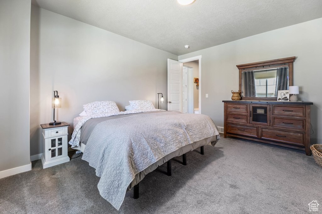 Bedroom with carpet, a textured ceiling, and baseboards