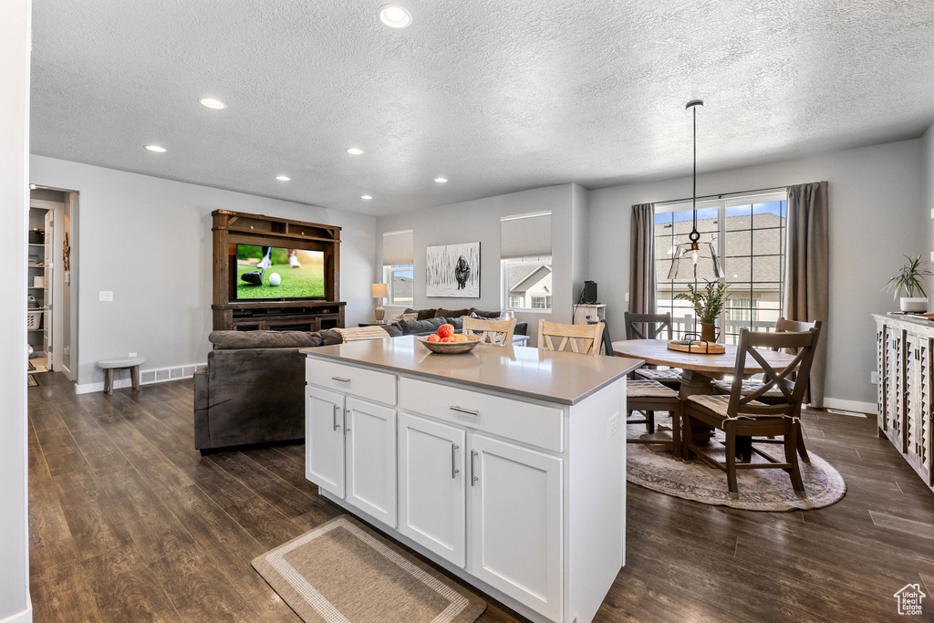 Kitchen featuring dark wood finished floors, recessed lighting, white cabinetry, a kitchen island, and baseboards