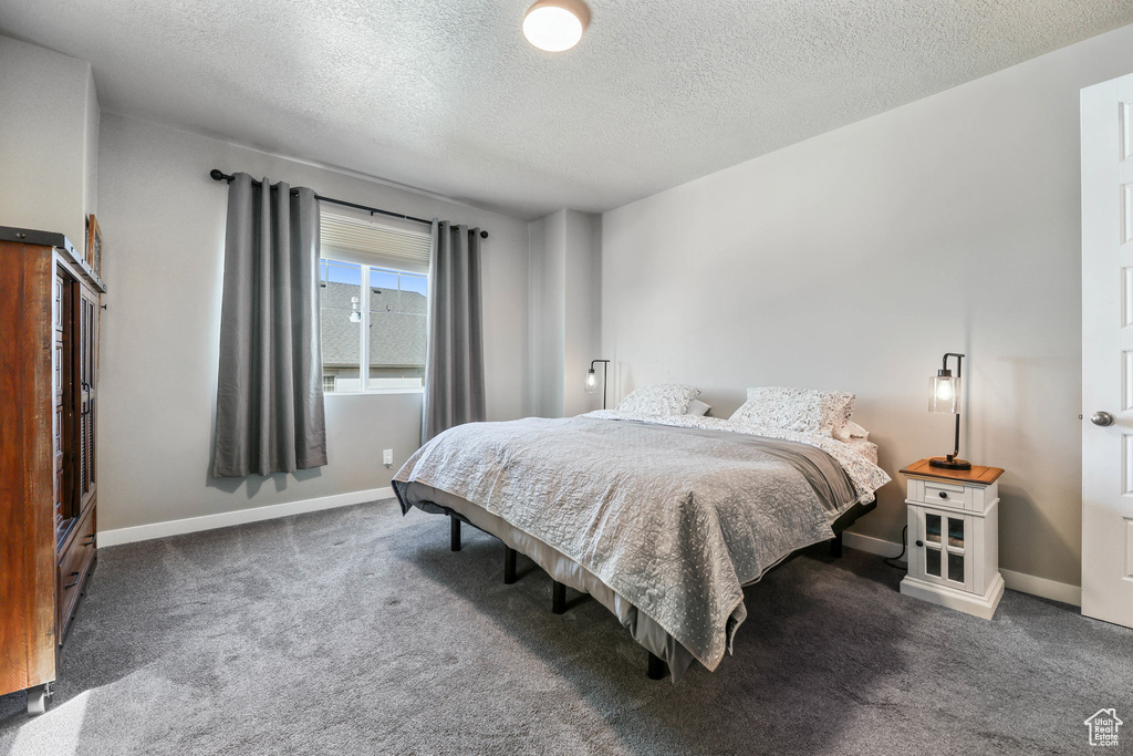 Carpeted bedroom featuring a textured ceiling and baseboards