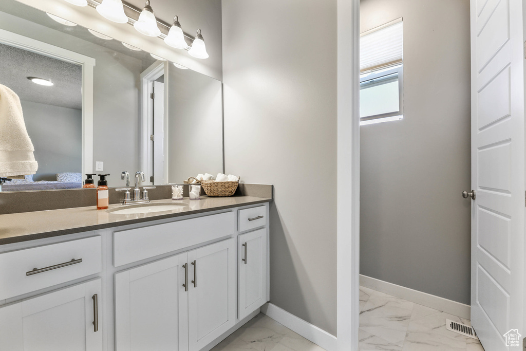 Bathroom with visible vents, baseboards, marble finish floor, a textured ceiling, and vanity