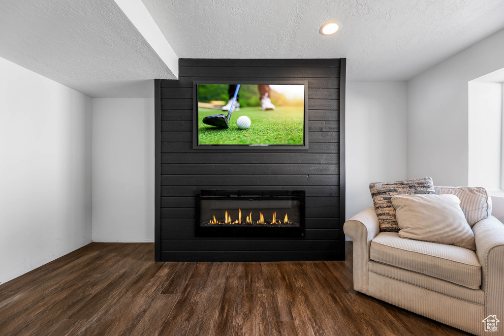 Living room with dark wood-style floors, a fireplace, and a textured ceiling
