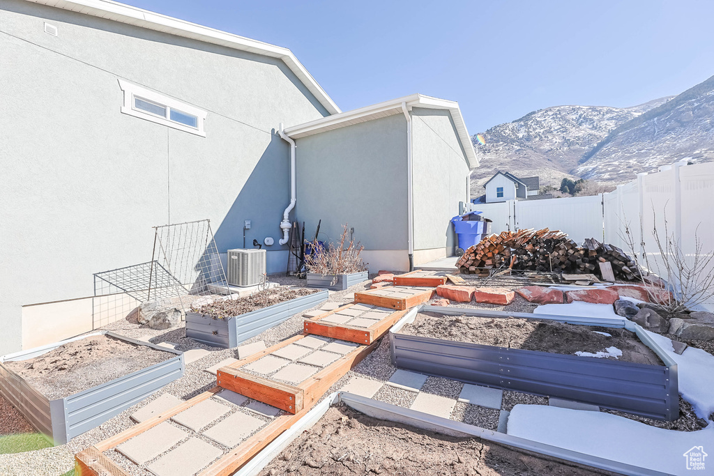 View of yard with a garden, fence, a mountain view, and cooling unit