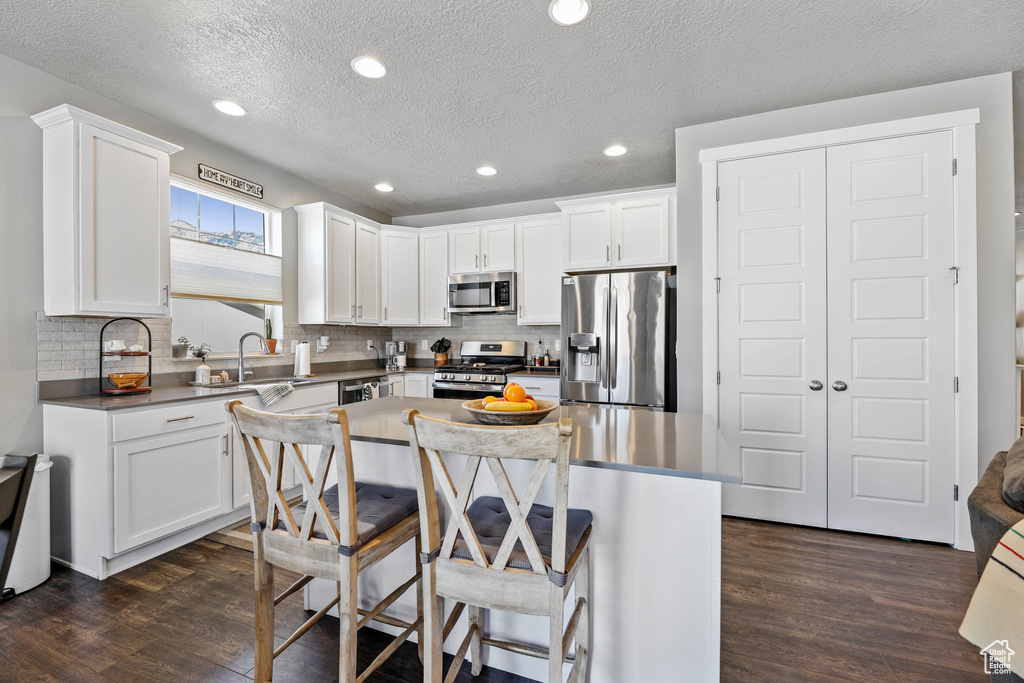 Kitchen with appliances with stainless steel finishes, dark wood-type flooring, and white cabinetry
