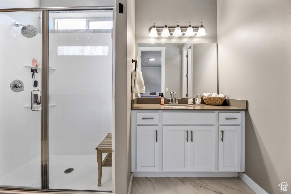 Bathroom featuring marble finish floor, a stall shower, vanity, and baseboards
