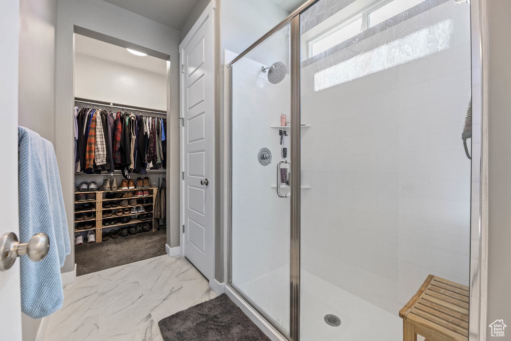 Full bath with marble finish floor, a shower stall, and a spacious closet