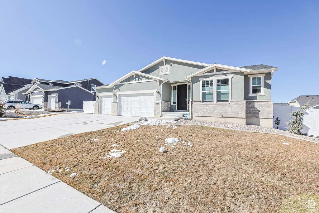 View of front of home with a garage, brick siding, fence, concrete driveway, and stucco siding