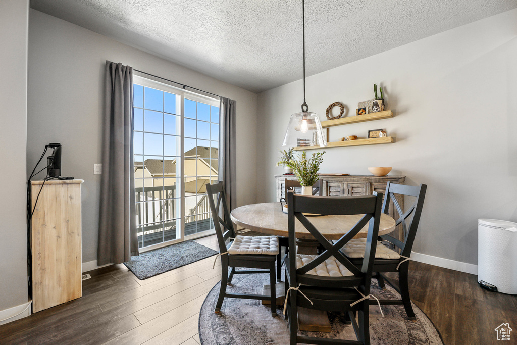 Dining space featuring a textured ceiling, baseboards, and wood finished floors