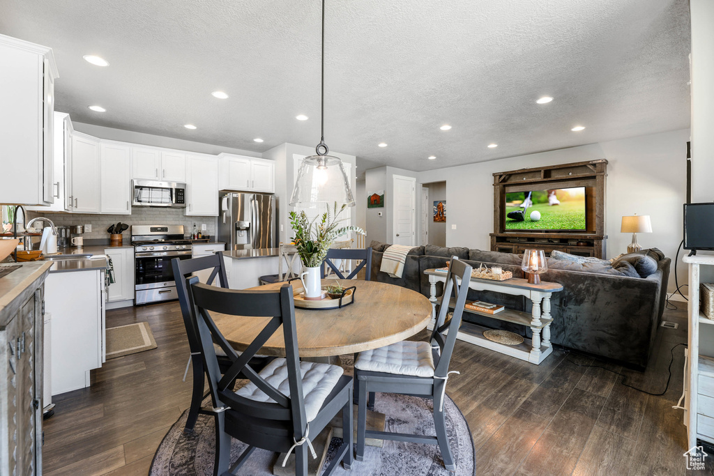 Dining room with dark wood-style floors, recessed lighting, and a textured ceiling