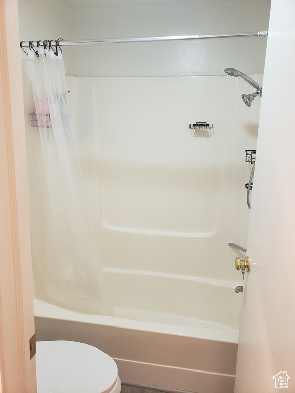 Bathroom featuring toilet and shower / bath combo with shower curtain