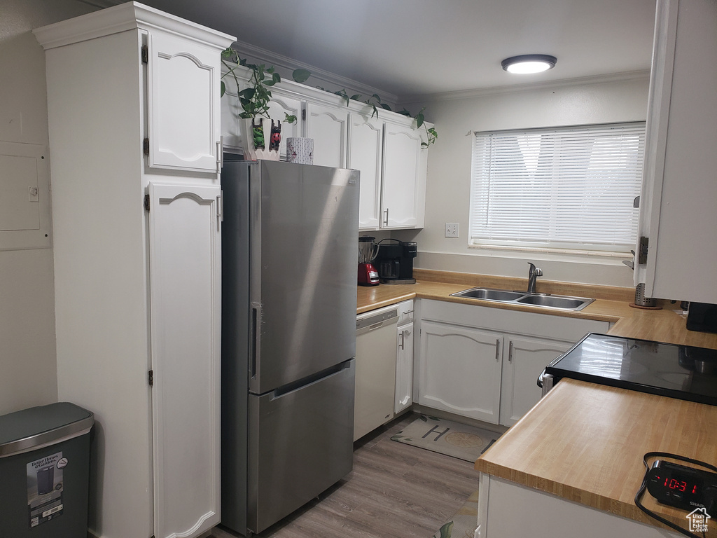 Kitchen featuring dishwasher, wood finished floors, freestanding refrigerator, white cabinetry, and a sink